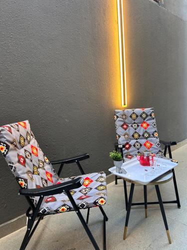 een paar stoelen en een tafel met een lamp bij شقة بدخول ذاتي وجلسة خارجية Midnight Apartment in Riyad