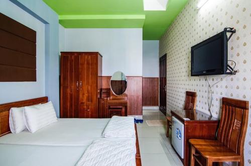 - une chambre avec 2 lits, une télévision et un bureau dans l'établissement Khách Sạn Huỳnh Anh, à Hô-Chi-Minh-Ville