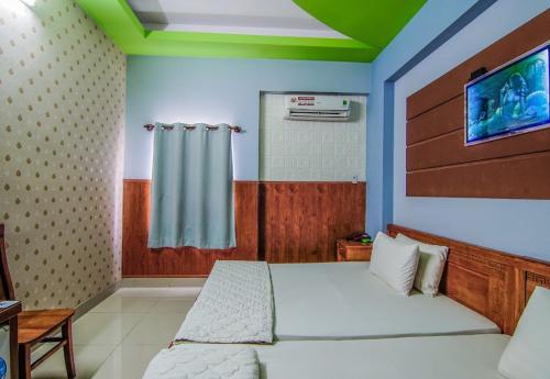 - une chambre avec un lit et une télévision murale dans l'établissement Khách Sạn Huỳnh Anh, à Hô-Chi-Minh-Ville
