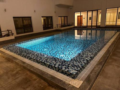 een groot zwembad met blauw water in een gebouw bij City Gem - Qurm in Muscat
