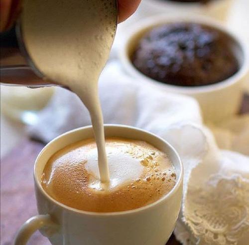 una persona sta versando latte in una tazza di caffè di Adriatic Luxury Suites a Pescara