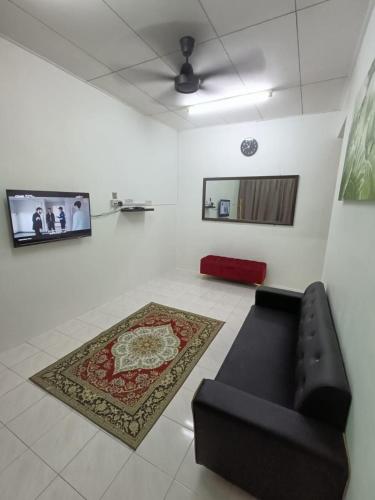 a living room with a black couch and a rug at Adempuri Homestay 3 in Jitra