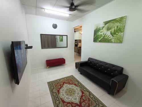 a living room with a black couch and a flat screen tv at Adempuri Homestay 3 in Jitra