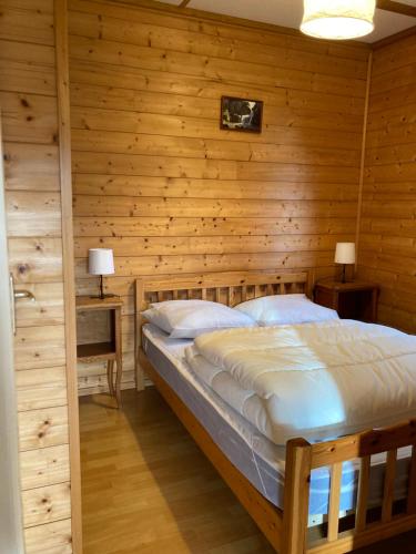 een slaapkamer met een bed in een houten muur bij Camping-Chalets La Favière in Lac des Rouges Truites