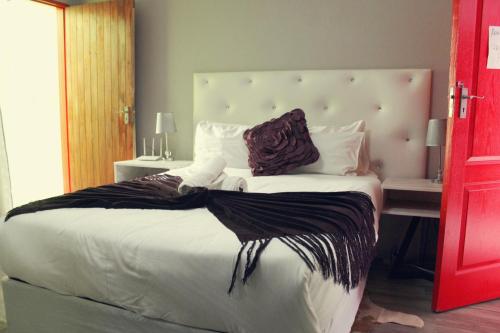 1 dormitorio con 1 cama grande y cabecero grande en El DiVino Guesthouse, en Newcastle