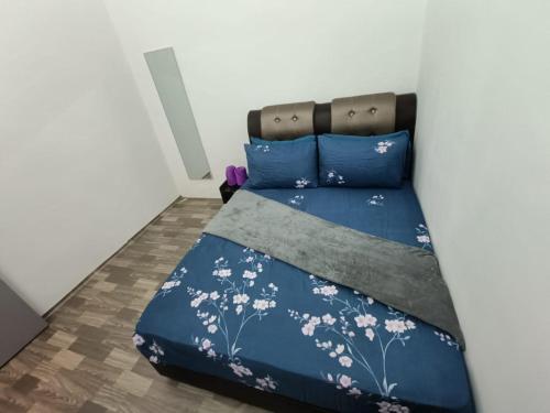 a bedroom with a bed with blue sheets and white flowers at Adempuri Homestay 3 in Jitra