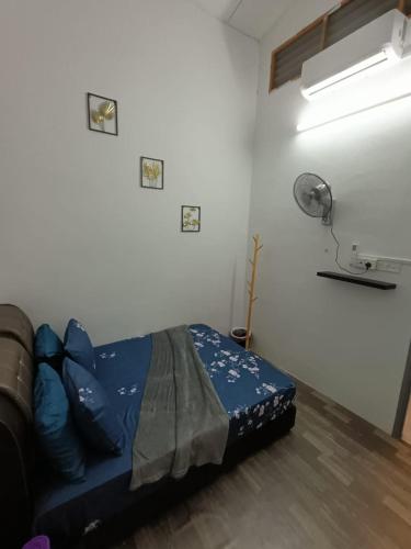 a bedroom with a bed with blue sheets and a fan at Adempuri Homestay 3 in Jitra