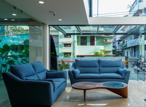uma sala de estar com dois sofás azuis e uma mesa de centro em The Trios Hotel em Cochin