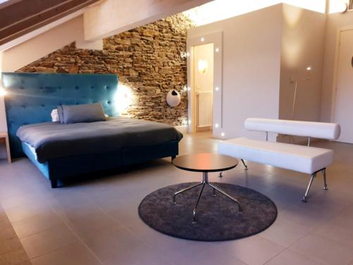 a bedroom with a bed and a table and a stone wall at Hotel Aracoeli in Orta San Giulio