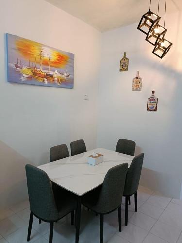 a dining room table with chairs and a painting on the wall at Adempuri Homestay 3 in Jitra