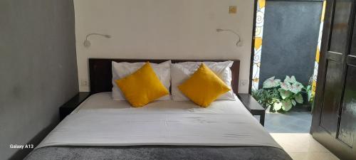 a bedroom with a bed with yellow pillows at Indah Homestay and Cooking classes in Senggigi