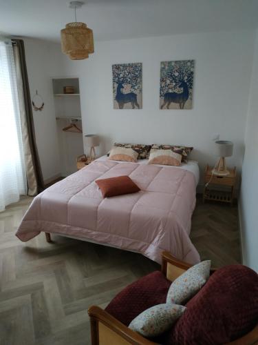a bedroom with a pink bed and two chairs at La maison d Eole in Saint-Sulpice-les-Champs