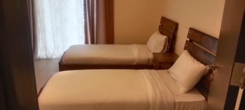 2 bedden in een hotelkamer met een raam bij DeadSea view apartments Samarah Resort E22 in Amman