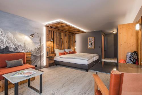 a bedroom with a bed and a couch and a table at BaseCamp Hotel in Zermatt