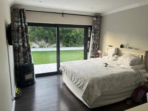 a bedroom with a large bed and a large window at Charming home, The Vines in Constantia in Cape Town