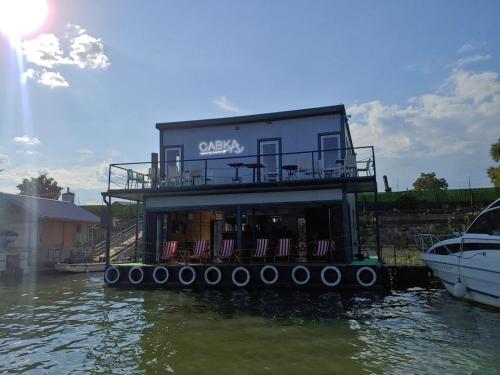 a house on a barge in the water with a boat at Savka Splav in Belgrade