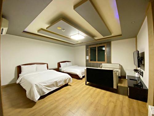 a hotel room with two beds and a flat screen tv at F1 Hotel in Mokpo