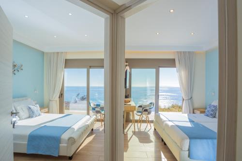 two beds in a room with a view of the ocean at Olive and Aloe Villas in Nomikianá