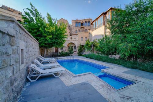a swimming pool with lounge chairs next to a building at Tekkaya Cave Hotel in Goreme