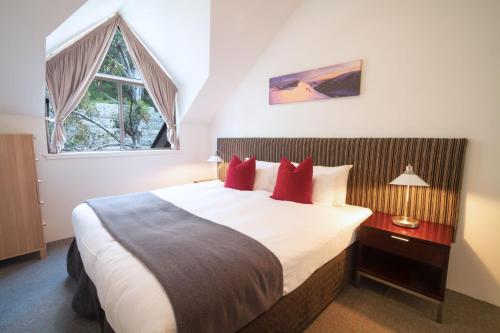 a bedroom with a large bed with red pillows at Lantern 1 Bedroom Balcony with Panoramic Alpine View in Thredbo