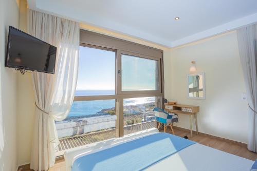 una camera da letto con una grande finestra con vista sull'oceano di Olive and Aloe Villas a Nomikianá