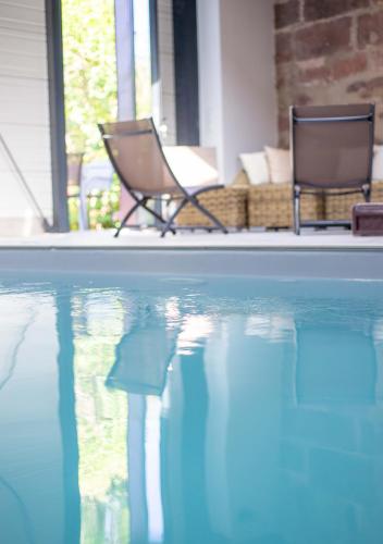 two chairs are sitting next to a swimming pool at Gîte La Tour des Remparts Pool & Jacuzzi in Saverne