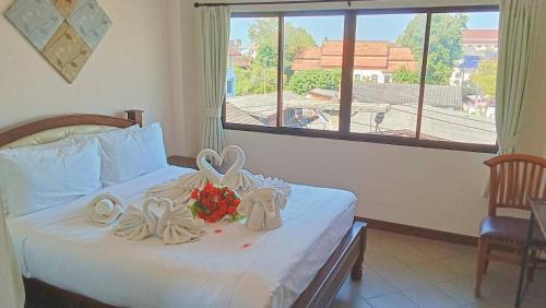 a bedroom with a bed with towels and flowers on it at The Guest Hotel & Hostel in Chiang Mai