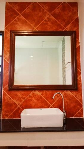 a mirror above a white sink in a bathroom at The Guest Hotel & Hostel in Chiang Mai