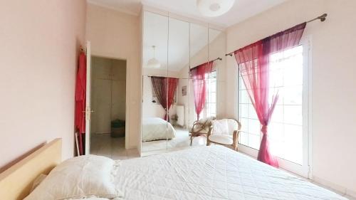 Schlafzimmer mit einem weißen Bett und roten Vorhängen in der Unterkunft House Angie in Porto Rafti
