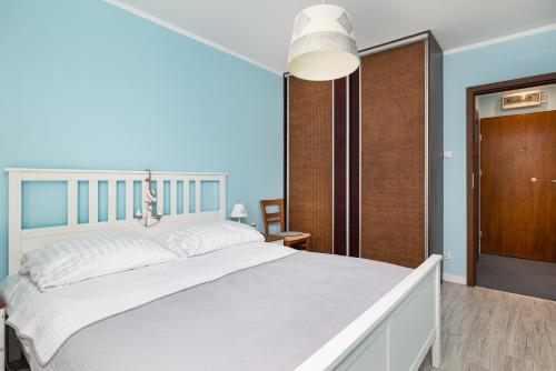 a bedroom with a large white bed and blue walls at Maritime Cosy Apartment in Świnoujście