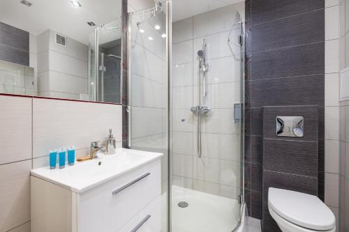 a bathroom with a shower and a toilet and a sink at Maritime Cosy Apartment in Świnoujście