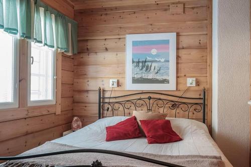 1 dormitorio con pared de madera y cama con almohadas rojas en Villa Ojala, a lovely cottage with own beach, en Kuusamo