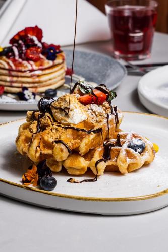 a plate of waffles with fruit and syrup on a table at Park hall Hotel & Spa Lancashire, a member of Radisson Individuals in Eccleston