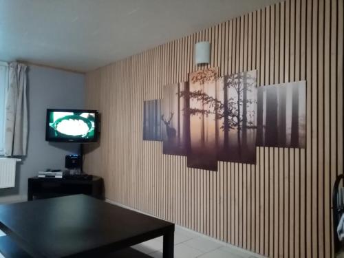 Gîte de la barrière في Libin: غرفة معيشة مع طاولة وتلفزيون