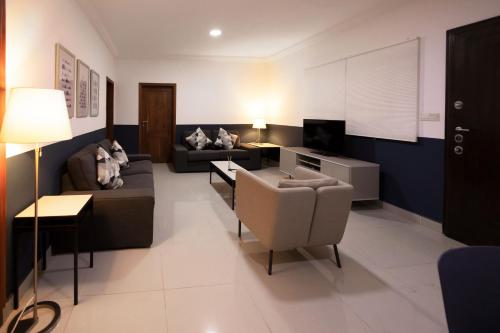 a living room with a couch and a tv at Bragha Apartments And Hotel in Takoradi
