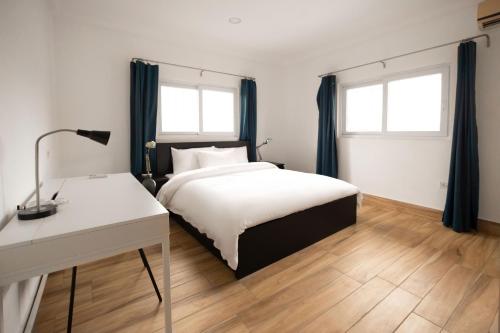 塔科拉迪的住宿－BRAGHA APARTMENTS，一间卧室配有一张床、一张书桌和两个窗户。
