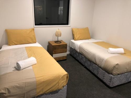 Dos camas en una habitación pequeña con ventana. en addington luxury townhouse, en Christchurch