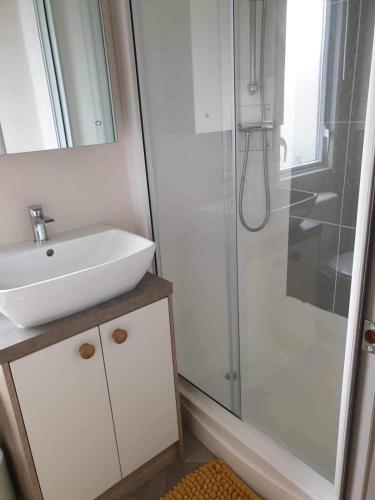 La salle de bains blanche est pourvue d'un lavabo et d'une douche. dans l'établissement hot tub luxury caravan 23 Lancaster tattershall lakes, à Tattershall