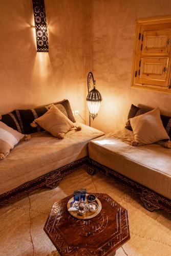a living room with two beds and a table at Dar Sofar in Agdz