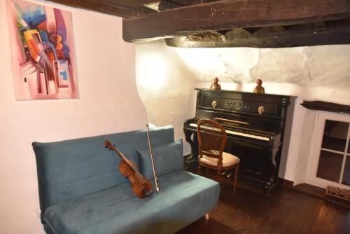 a living room with a blue couch and a piano at Gite Ardennes Au coin du feu jacuzzi sauna et nature in Jalhay