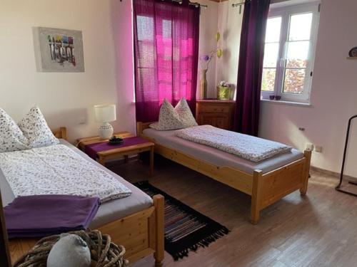 a room with two beds and a window with purple curtains at Haus Betty in Rattelsdorf