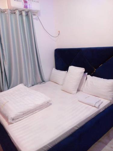 Una cama azul con almohadas blancas encima. en CHARLES GROOVE HOTEL, 