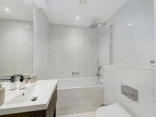 La salle de bains blanche est pourvue d'un lavabo et d'une baignoire. dans l'établissement Fabulous- beach 10 mins, roof tce, wifi, pkg, 3 tv, à Christchurch