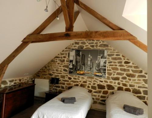 2 Betten in einem Zimmer mit einer Steinmauer in der Unterkunft LOFT au cœur de Bécherel in Bécherel