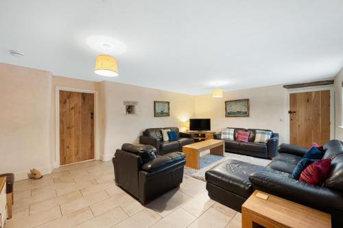 a living room with leather couches and a television at Host & Stay - The Barn - Upper Farm in Tideswell