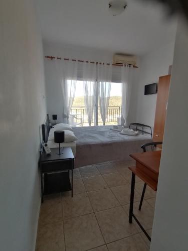 a bedroom with a bed and a large window at Calypso Apartments in Vathi, Ithaka