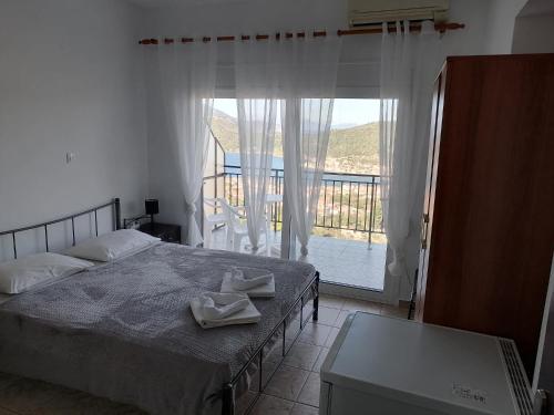 a bedroom with a bed and a balcony with a view at Calypso Apartments in Vathi, Ithaka