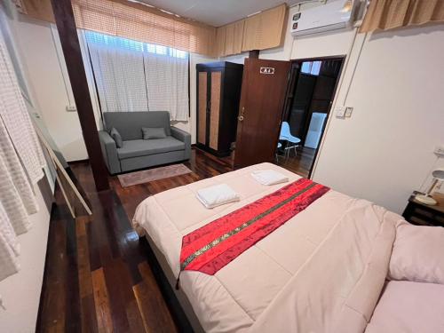 a bedroom with a bed and a couch and a chair at Allred Hostel Chiangmai in Chiang Mai