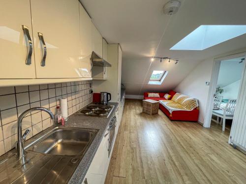 una cocina con fregadero y un sofá en una habitación en 1 Bed Attic Flat with Easy Reach to City Centre, en Londres