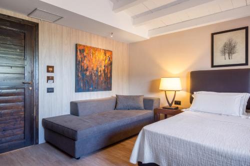 a bedroom with a bed and a couch and a table at Vallegrande Nature Resort by Geocharme in Cefalù